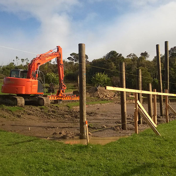 Hydraulic excavator prepares building platform after completion of geotech report.